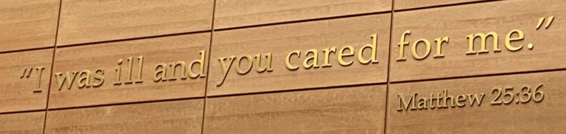 Quote on the atrium wall of Loyola Chicago’s Cuneo Center reading, ‘I was ill and you cared for me. - Matthew 25:36.’